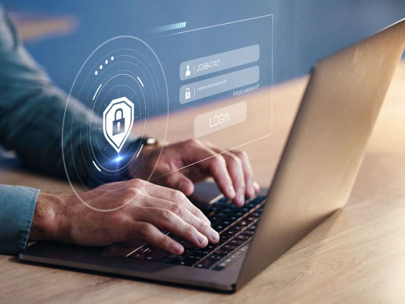 Person typing on a laptop with a digital login interface and lock icon overlay.