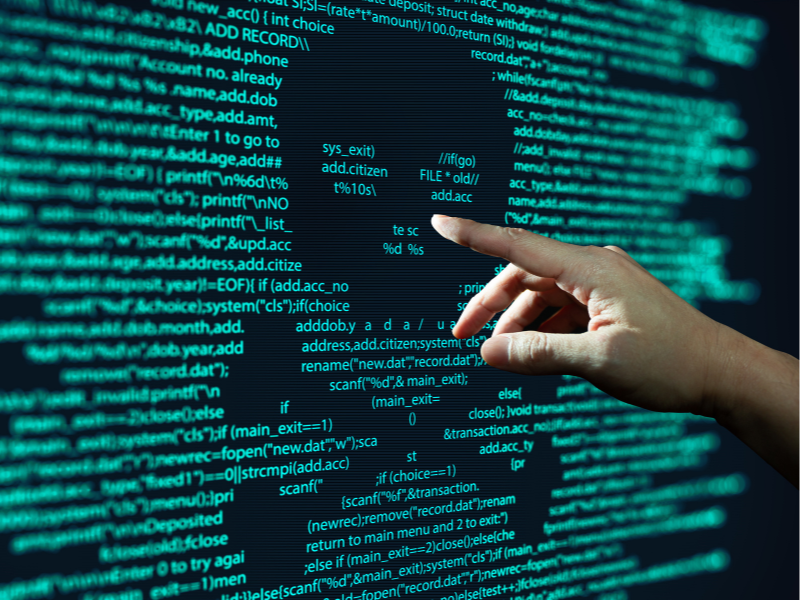 A hand pointing at green text on a black computer screen.