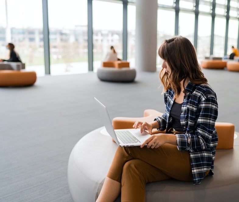 happy-woman-using-lap-top-while-sitting-airport-lounge-cropped