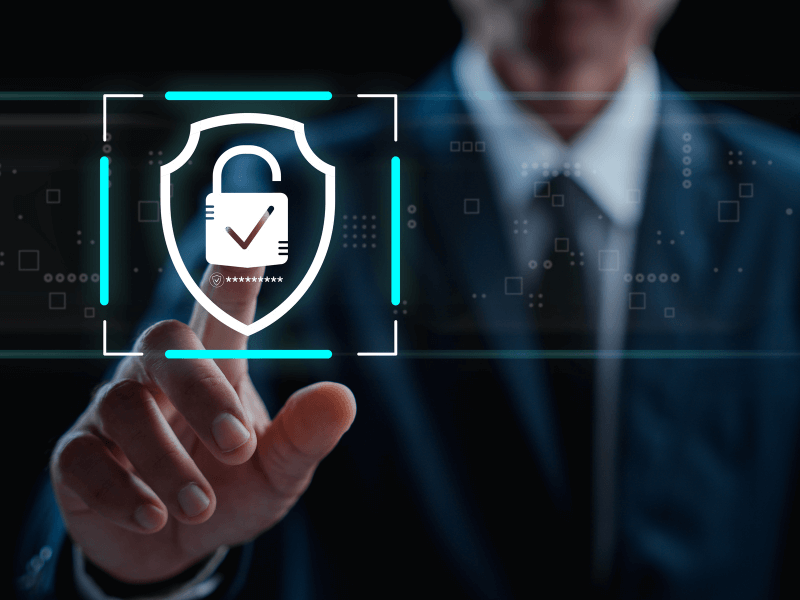 A person in a suit touching a digital screen with a security shield and padlock graphic